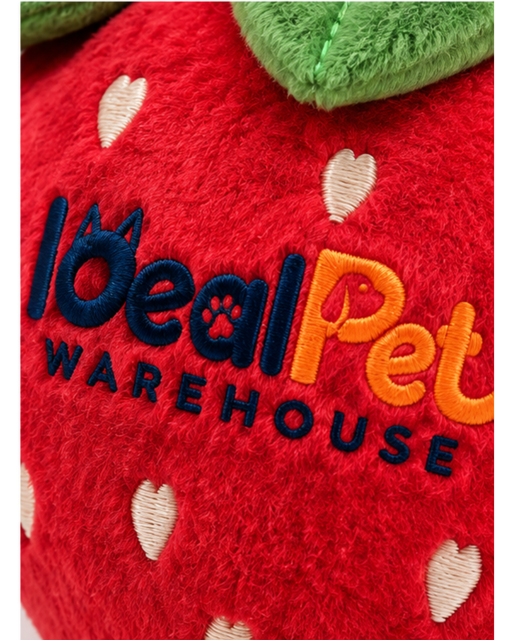 Close-up of the embroidered logo and seed stitching on the red strawberry plush